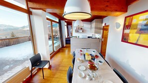 A dining area with a table set for four, a chair, and a view of a snowy landscape through large windows. - Luxury apartment at the base of the slopes, 4 bedrooms, terraces with views of Mont Blanc, Arcs 1800 (Bourg-Saint-Maurice)