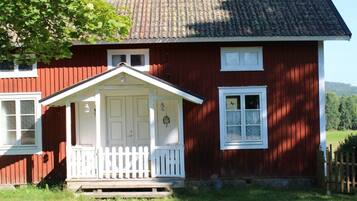 Ein rotes Holzhaus mit weißer Veranda und einem kleinen Vorgarten.