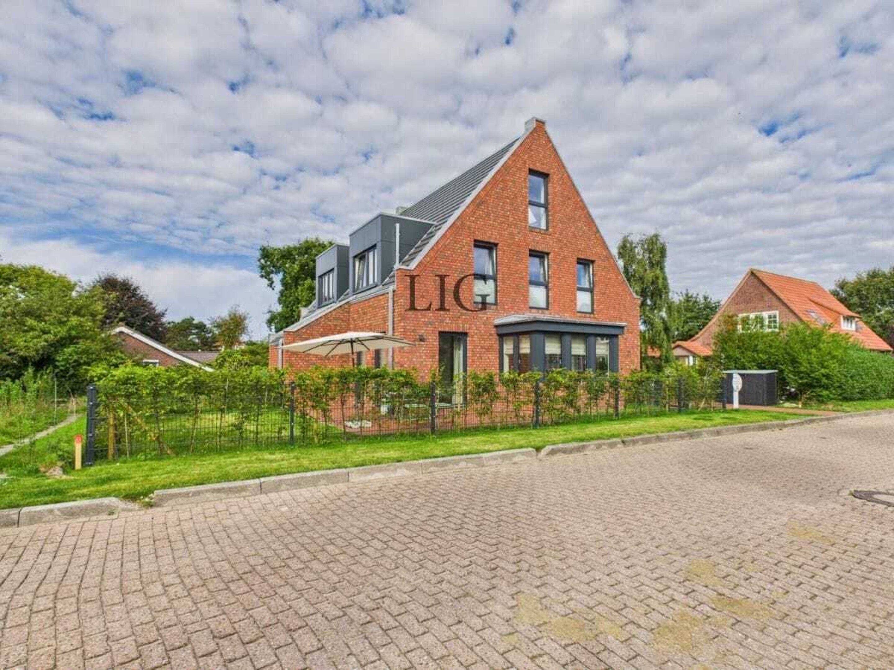 A red-brick house with a sloped roof, a visible garage, and a paved driveway.