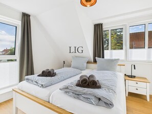 Ein Schlafzimmer mit zwei Betten, einem Nachttisch und einem Fenster mit Vorhängen.