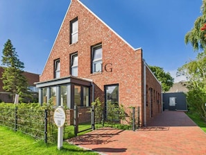 Ein modernes Ziegelgebäude mit einem markanten 'LG'-Schild, einem verschlossenen Eingang und blauem Himmel.