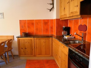 A kitchen with wooden cabinets, a stove, and a sink. - Paradies 026 Appartement/Fewo, Bad, WC, 4-Bettwohnung 4-Bettwohnung by Interhome (Arosa)