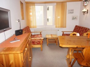 A room with a wooden dining table, two chairs, a sofa, a television, and a radiator. - Paradies 026 Appartement/Fewo, Bad, WC, 4-Bettwohnung 4-Bettwohnung by Interhome (Arosa)