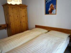 A bedroom with a wooden wardrobe and a poster on the wall. - Paradies 026 Appartement/Fewo, Bad, WC, 4-Bettwohnung 4-Bettwohnung by Interhome (Arosa)