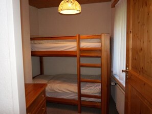 A bunk bed room with a wooden ladder, a small wooden dresser, and a radiator. - Paradies 026 Appartement/Fewo, Bad, WC, 4-Bettwohnung 4-Bettwohnung by Interhome (Arosa)