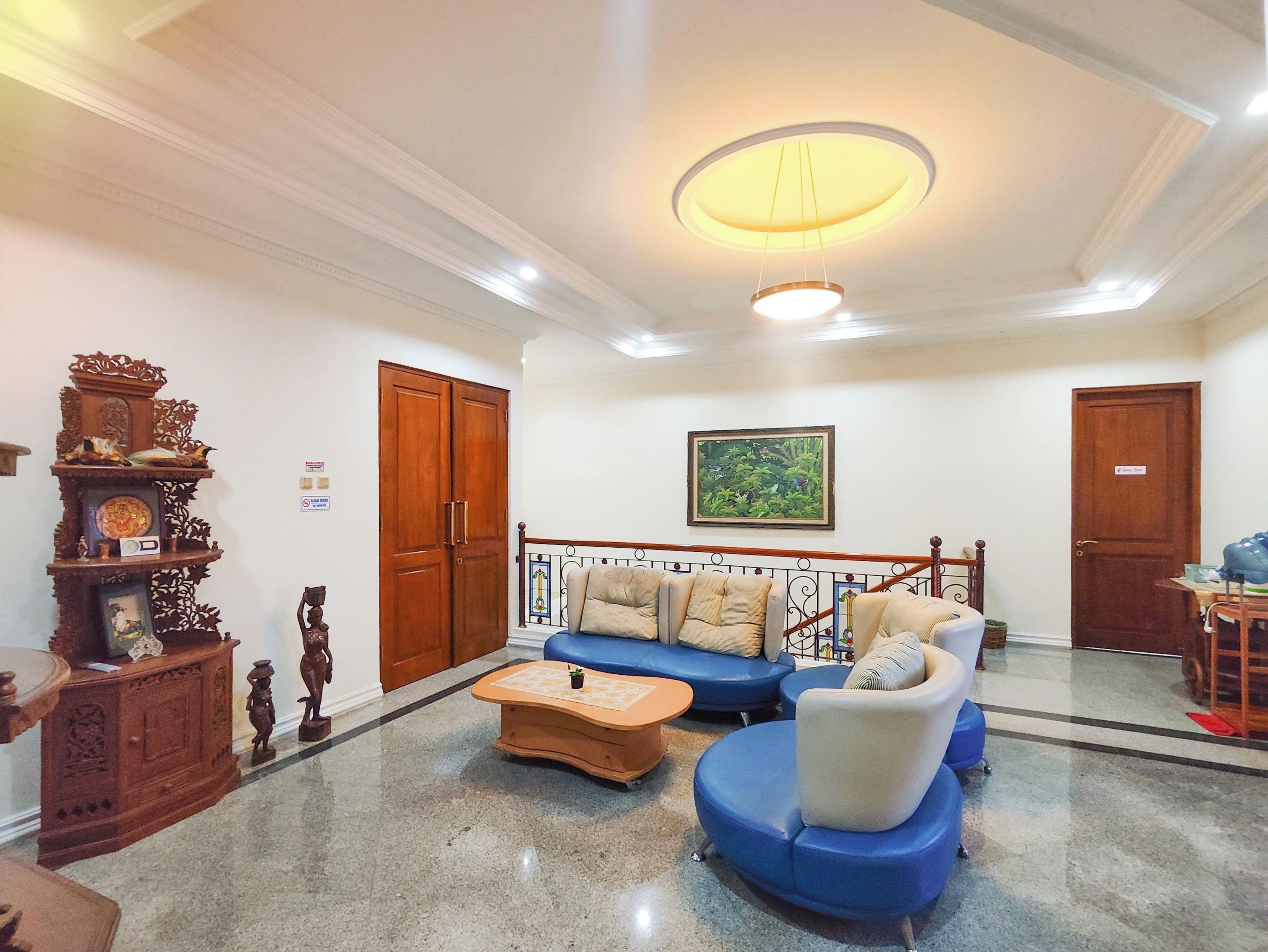 A room with a sofa set, a wooden cabinet with decorative items, and a ceiling light fixture.