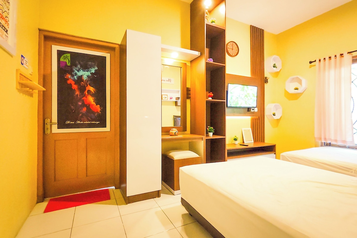 Een hotelkamer met een bed, een bureau, een televisie en een deur met een poster.