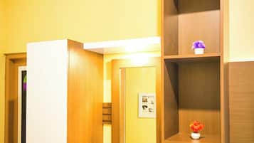 Una habitación con tocador de madera, un espejo y repisas con objetos decorativos.