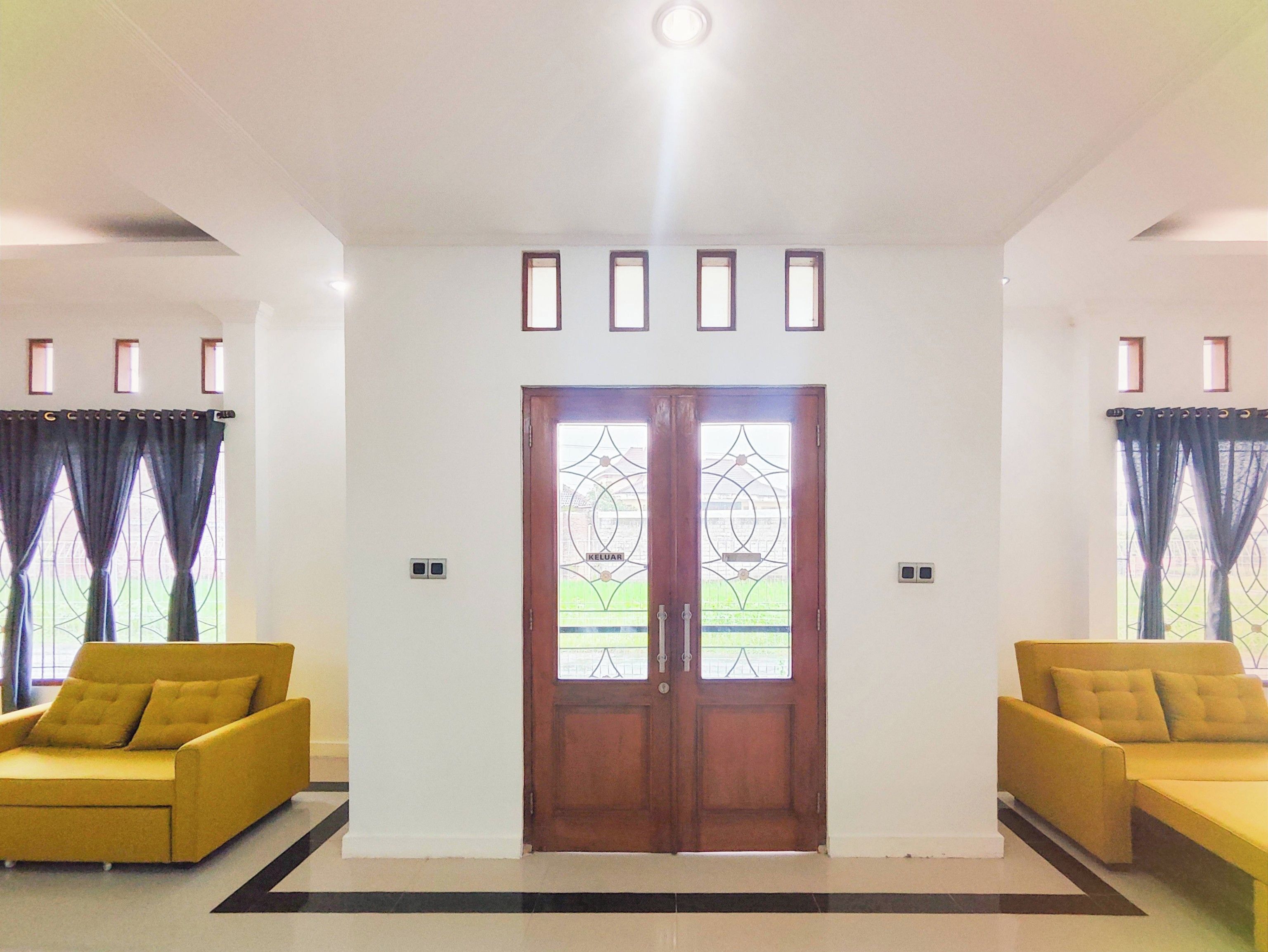 Una habitación con un puertas dobles, dos sofás y piso de baldosas.