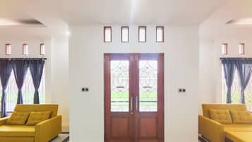 Una habitación con un puertas dobles, dos sofás y piso de baldosas.