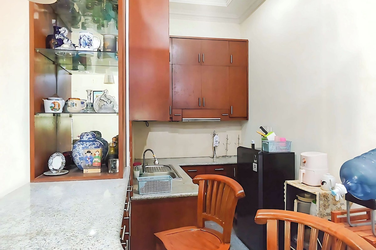 A kitchen with granite countertops, wooden cabinets, a sink, and a dining area with two wooden chairs.
