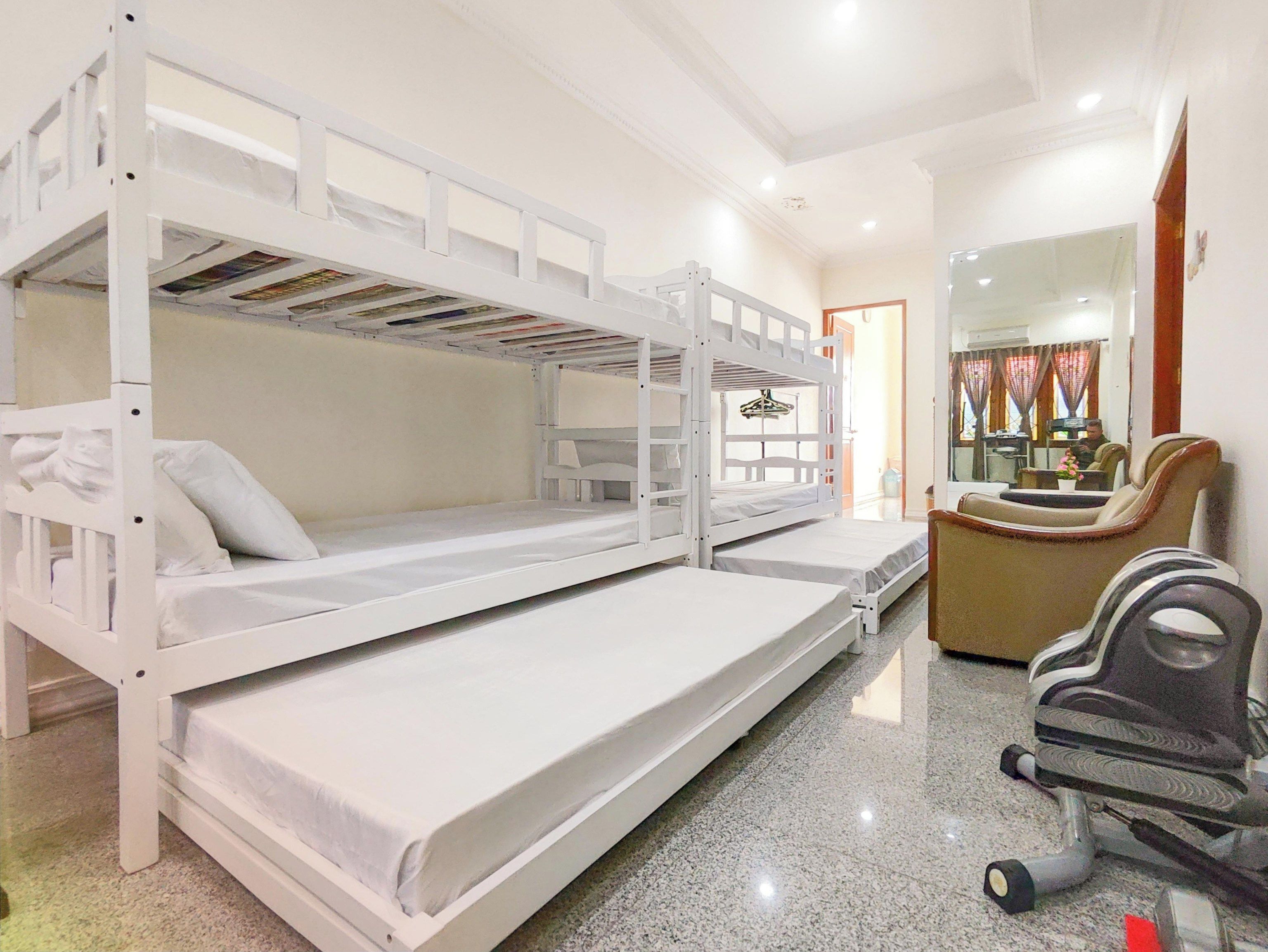 A bunk bed room with a desk and chair, a mirror, and a window with curtains.