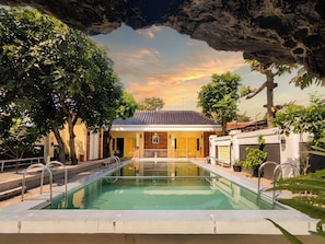 A swimming pool with a view of a building and trees. - Palma Villa Homestay Klaten (Klaten)