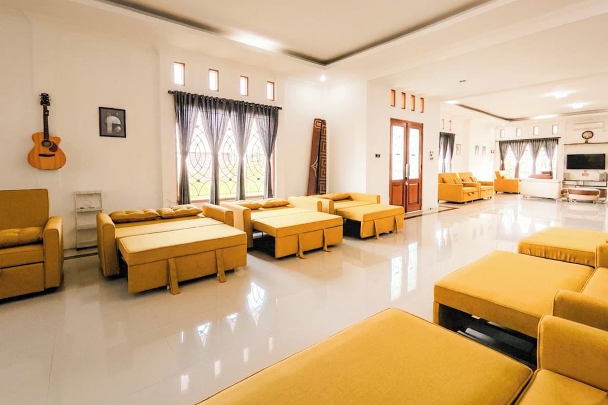 A spacious living area with multiple seating options, including sofas and a couch, arranged around a central coffee table.