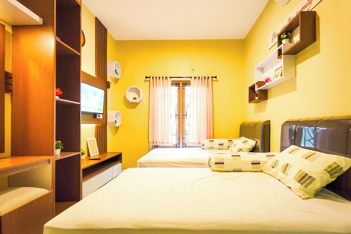 A hotel room with a bed, a desk, a TV, and a window with curtains.
