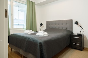 Ein Schlafzimmer mit einem Bett, Nachttischen, einem Fenster mit Vorhängen und einer Aussicht.
