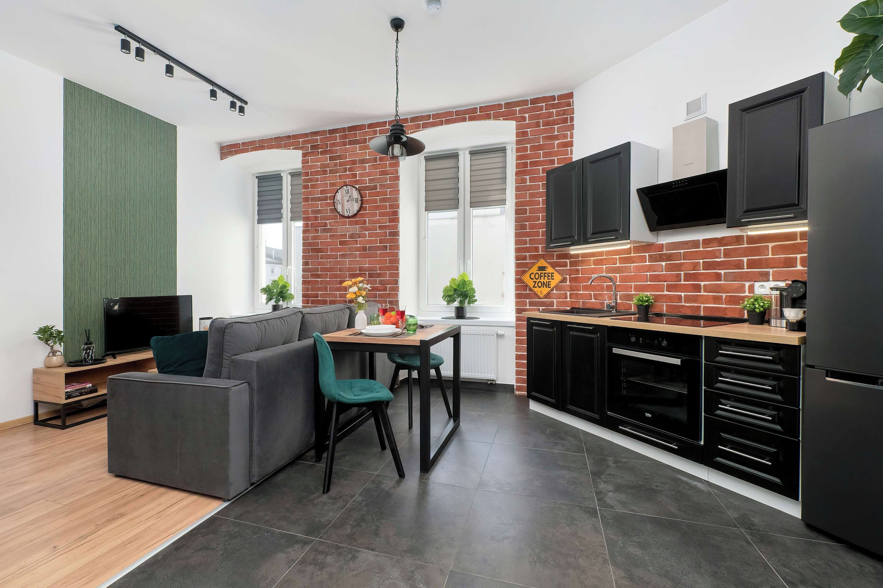 Eine moderne Küche mit Backsteinwand, schwarzen Schränken und einem eingebauten Ofen.