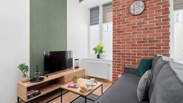 Ein modernes Wohnzimmer mit Flachbildfernseher, Couch, Couchtisch und einer Ziegelwand mit Uhr.
