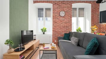 Ein Wohnzimmer mit Backsteinwand, einer Couch, einem Fernseher und einer Uhr.