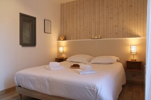 A neatly made bed with white linens and towels, two bedside lamps, and a wooden headboard. - Winds from the Open Sea (Cancale)