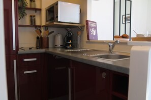 A kitchen with a microwave, coffee maker, and a book titled 'La Fabulueuse Cuisine'. - Winds from the Open Sea (Cancale)