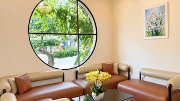 A modern living room with a sectional sofa, a glass coffee table, and a large window with a view of greenery.