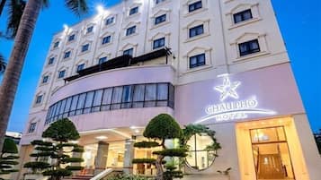 Un hotel con fachada moderna, un logotipo destacado y una entrada bien iluminada.