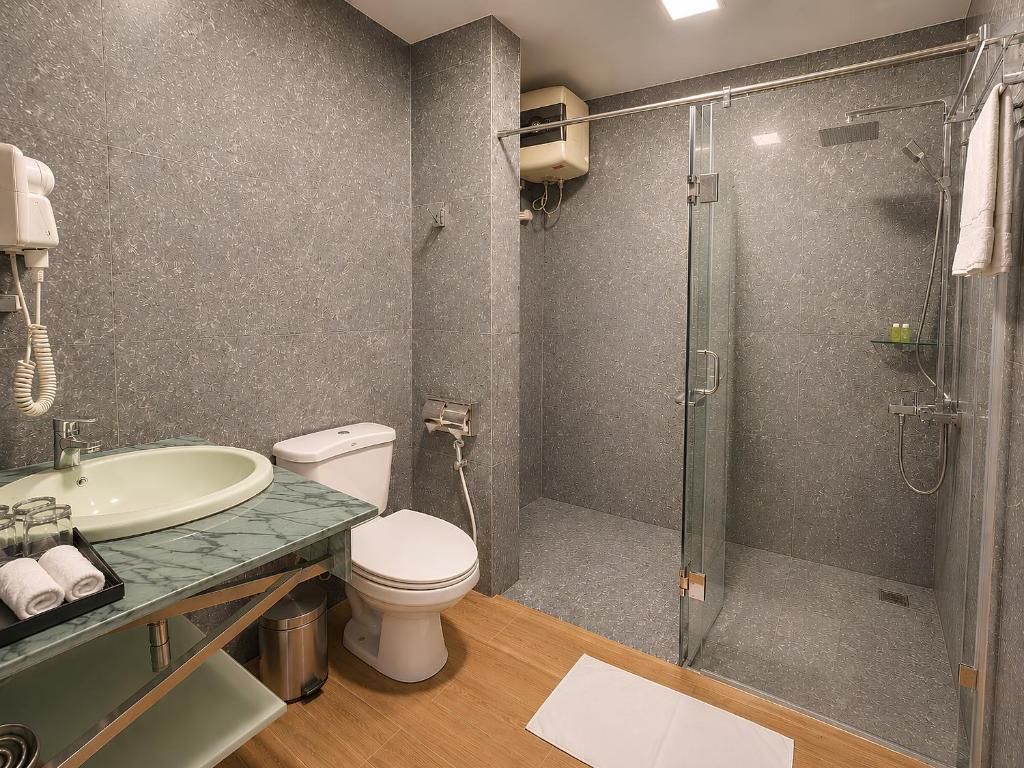 Un baño moderno con cabina de ducha de vidrio, inodoro y lavabo con encimera de mármol.