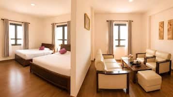 A hotel room with two beds, a sofa set, a coffee table, and a dining table.