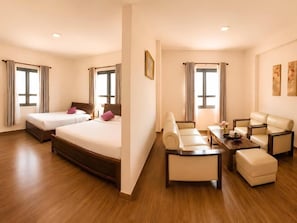 Habitación de hotel con dos camas, un sofá, una mesita de centro y una mesa de comedor.
