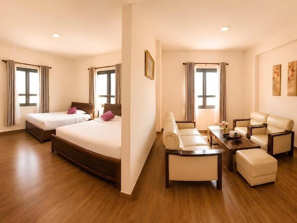 A hotel room with two beds, a sofa set, a coffee table, and a dining table.