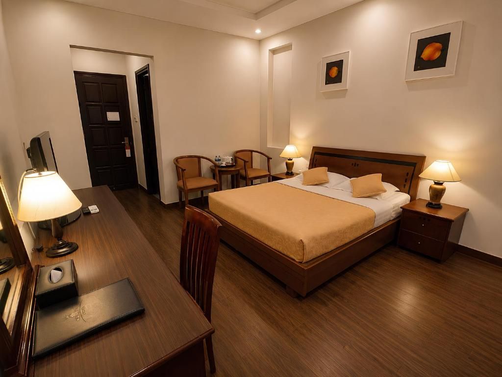 Una camera d'albergo con un letto, comodini, una scrivania e una sedia.