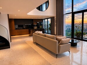 A modern living room with a sofa, a kitchen area, and large windows offering a city view. - Solvira Pentstudio West Hanoi Center (Phu Thuong)