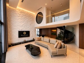 Una sala moderna con un sofá modular, una mesa de centro de mármol negro y un letrero que dice 'Pentstudio Manor'.