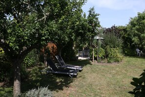 A garden with a patio area, including a table and chairs, surrounded by trees and greenery. - Ty Maine (Saint-Malo)