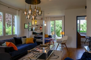 Uma sala de estar moderna com um sofá azul, uma mesa de centro de vidro e uma estante de livros.