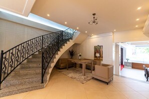 A spacious living area with a staircase, a dining table, and a sofa. - Hotel Princ (Golem)