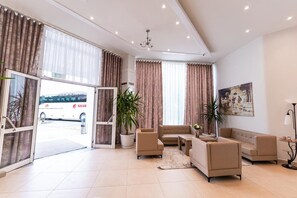 A spacious living area with a sofa set, a coffee table, and a potted plant. - Hotel Princ (Golem)