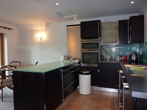 A modern kitchen with black cabinets, a glass island, and a stainless steel oven.