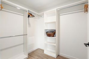 Ein begehbarer Kleiderschrank mit offenen Türen, Regalen und einer Kleiderstange.