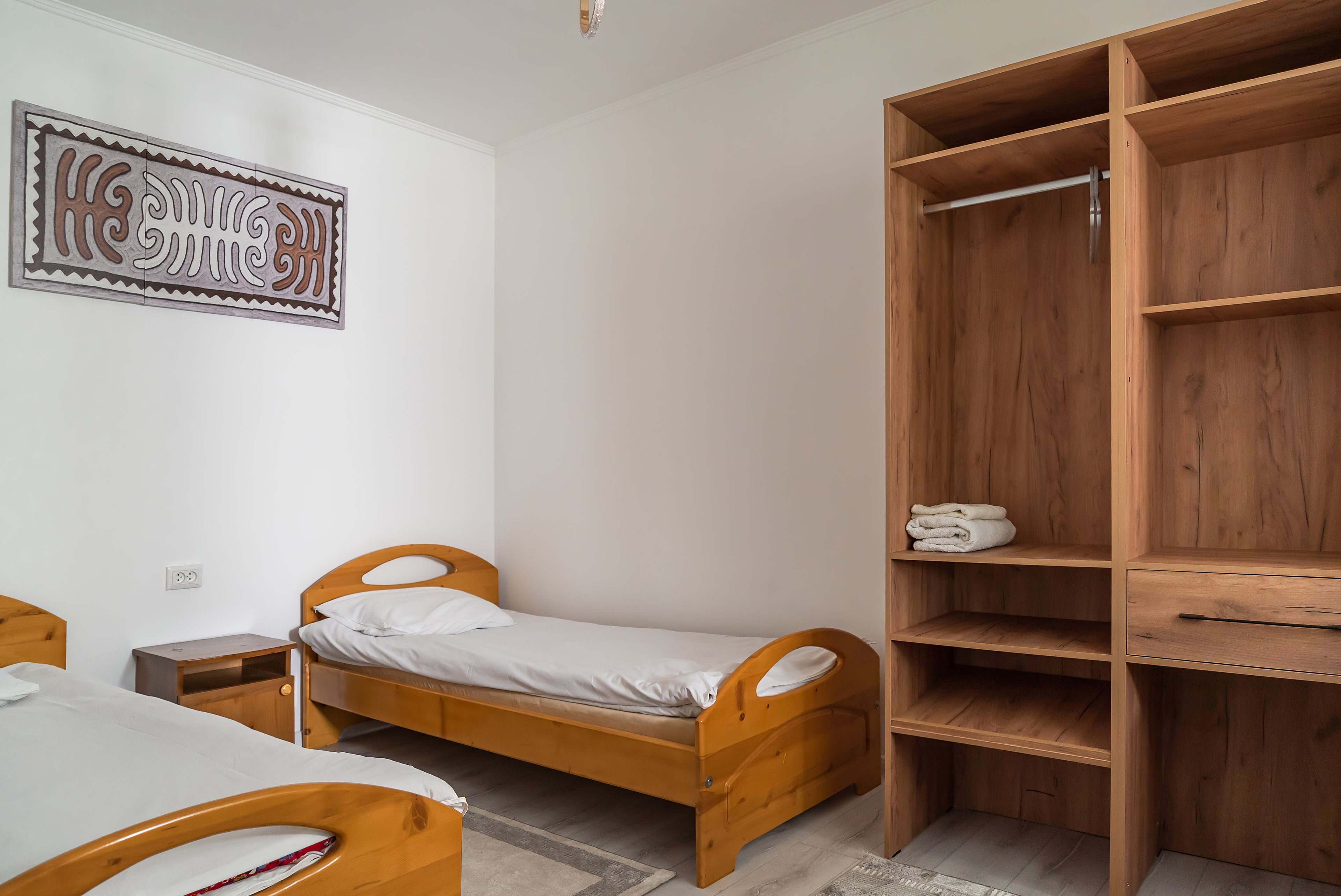 Un dormitorio con una cama individual, un armario de madera y una obra de arte colgada en la pared.