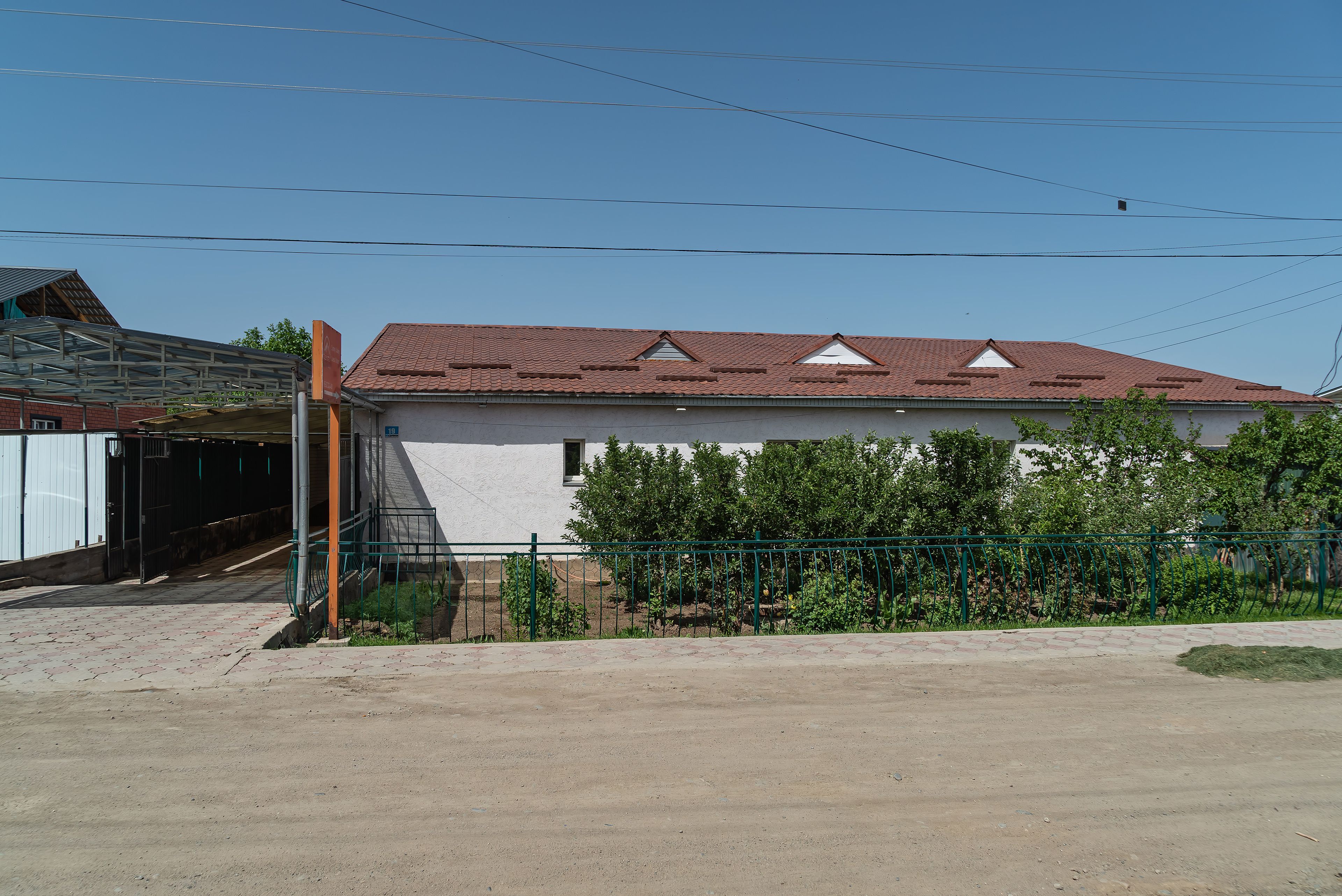A building with a red-tiled roof, a covered entrance, and a fenced garden area.