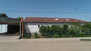 A building with a red-tiled roof, a covered entrance, and a fenced garden area.