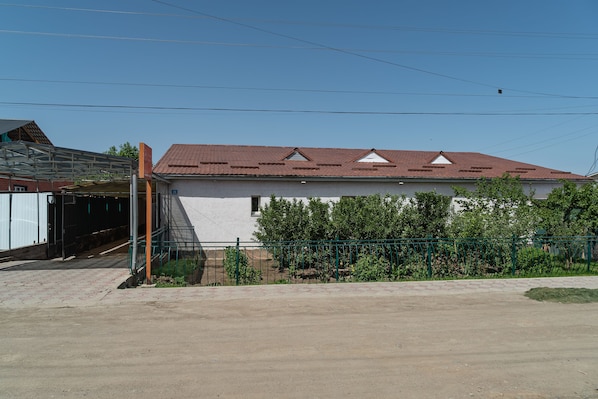A building with a red-tiled roof, a covered entrance, and a fenced garden area.
