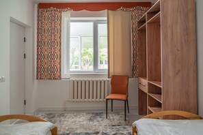 Une chambre à coucher avec un lit, une chaise, une armoire et une fenêtre avec des rideaux.