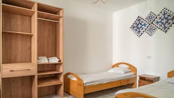 A bedroom with a wooden bed, a wooden wardrobe, a small bedside table, and a patterned rug.