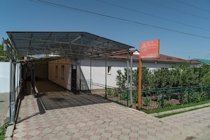 A building with a covered entrance, a signboard, and a paved pathway leading to the entrance.