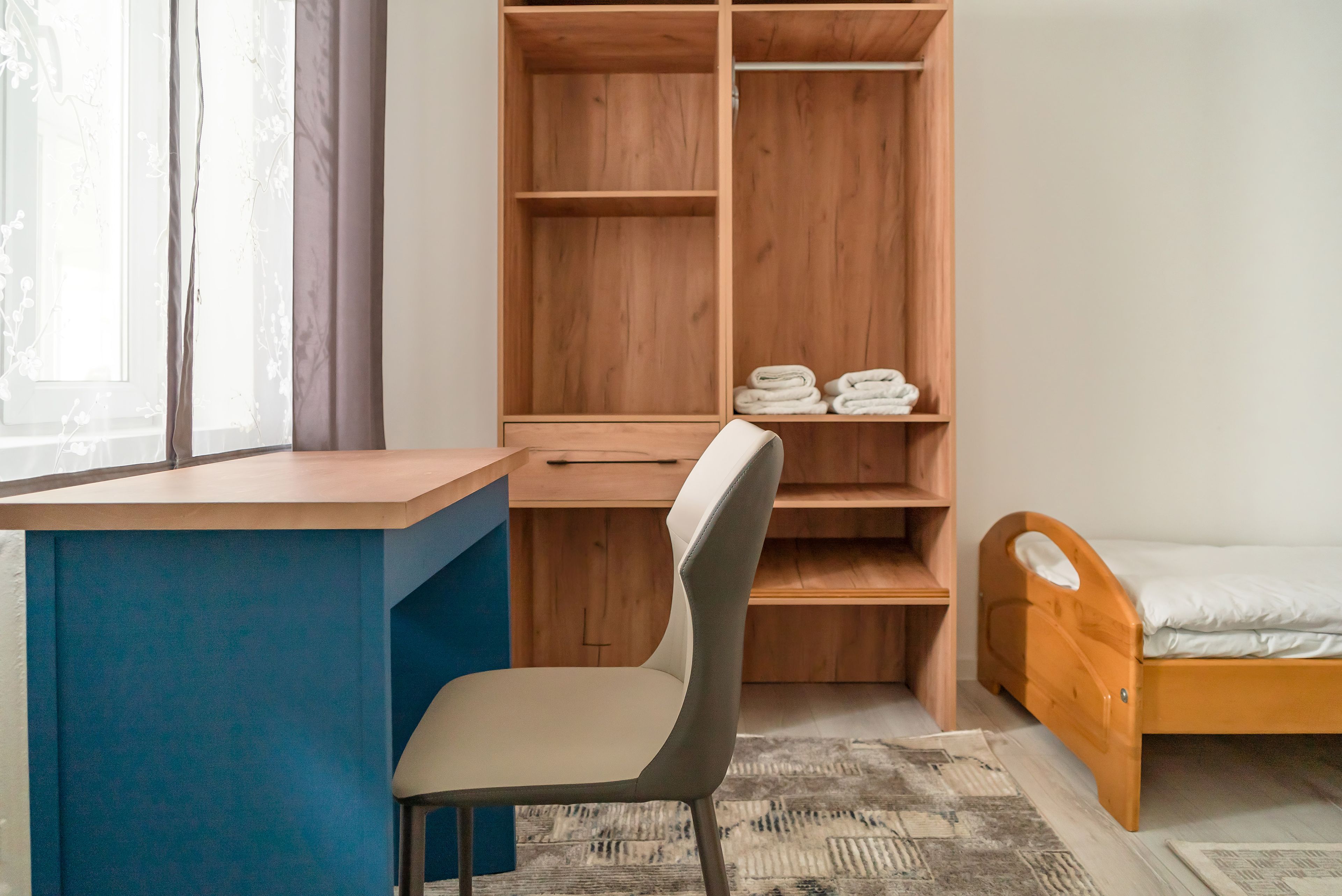 A bedroom with a wooden bed, a desk, and a chair.