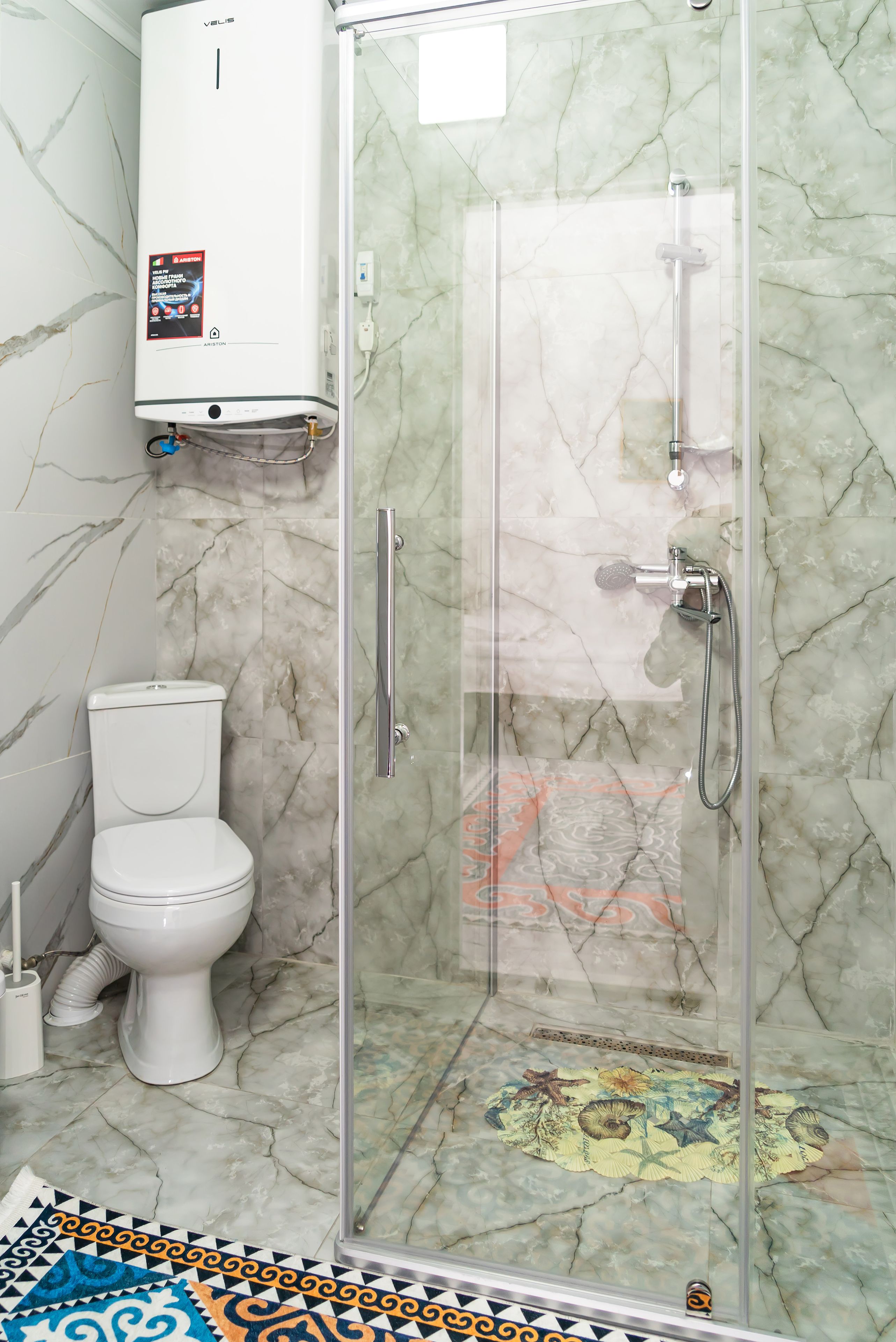 Un bagno con il water, box doccia e pavimento in marmo.