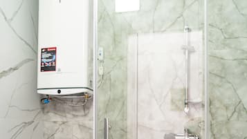 Een badkamer met een toilet, een douchecabine en een vloer betegeld met marmer.